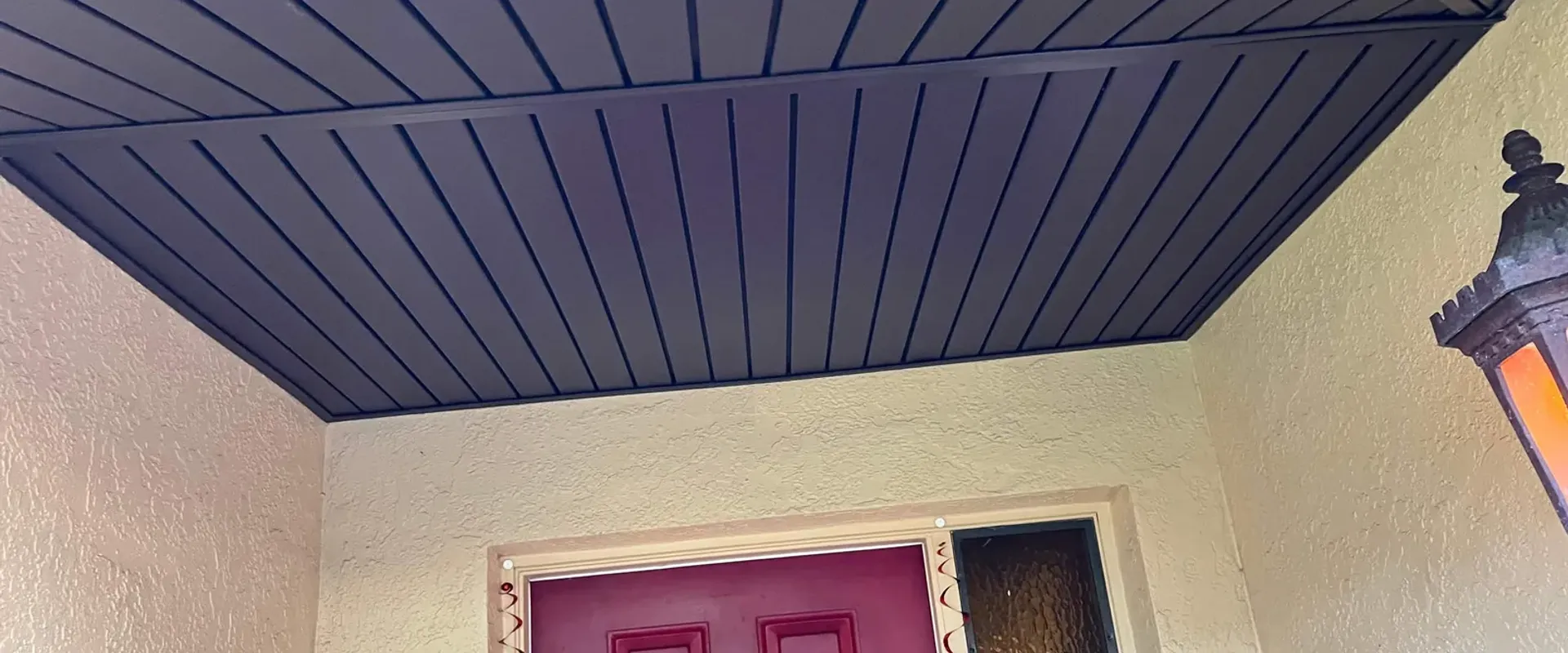 Dark brown beadboard ceiling treatment under a Tampa home entryway with a red door