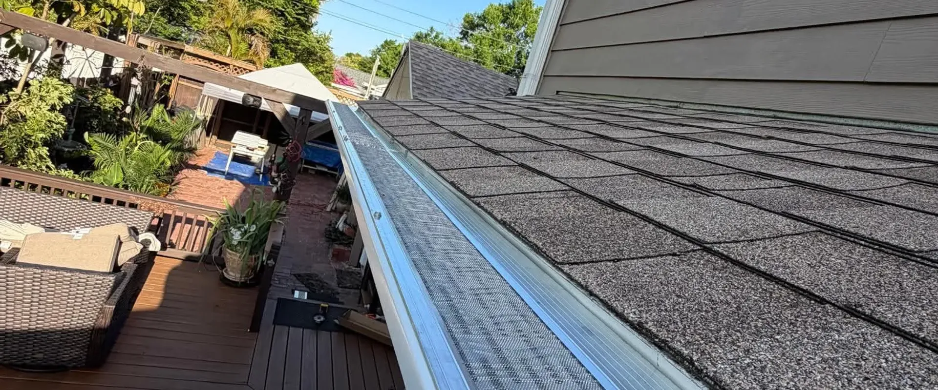 New aluminum gutters with leaf-guard mesh installed along the roofline of a two-story Tampa home with a deck below