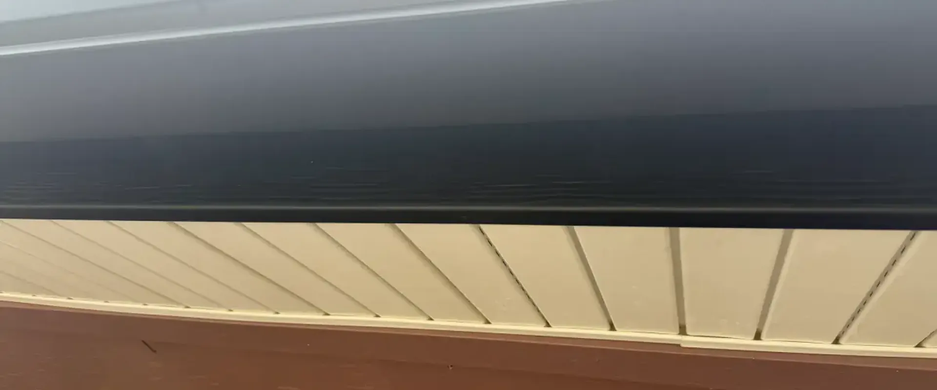 Close-up of dark navy aluminum fascia wrap above a cream hidden-vent soffit on a St. Petersburg home lanai