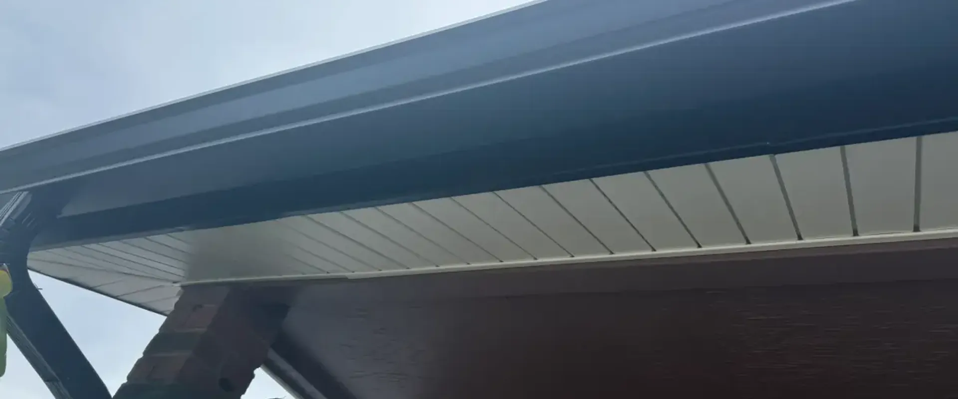 Dark navy aluminum fascia and white vented soffit on a brick-column carport at a St. Petersburg home