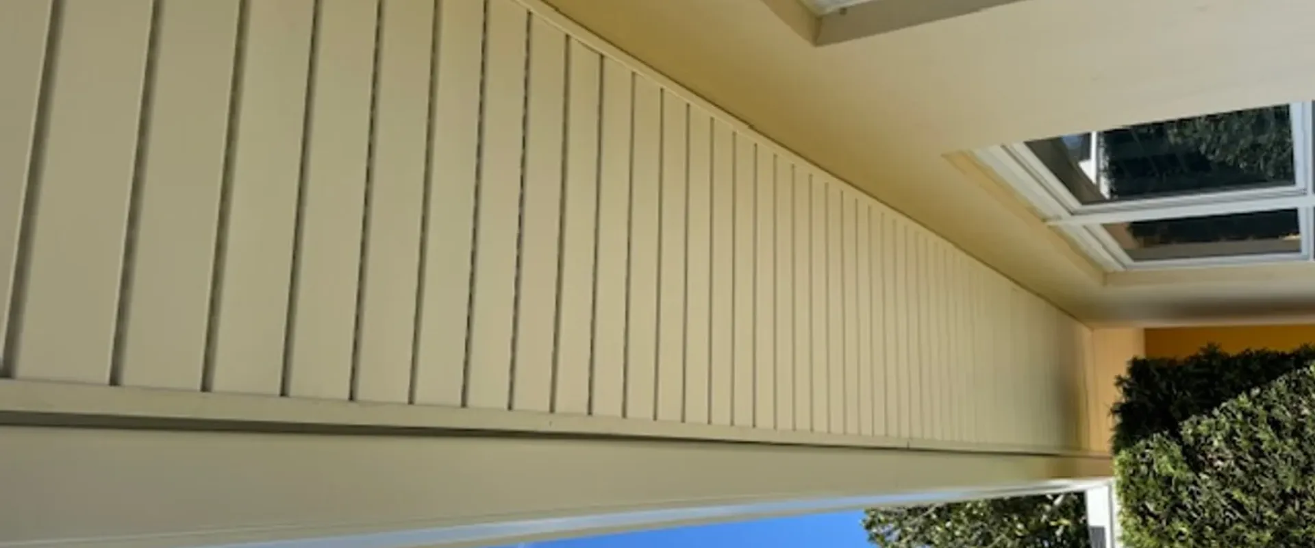 Cream vinyl soffit and white fascia installed along the eave of a yellow stucco Tampa Bay home with white window trim