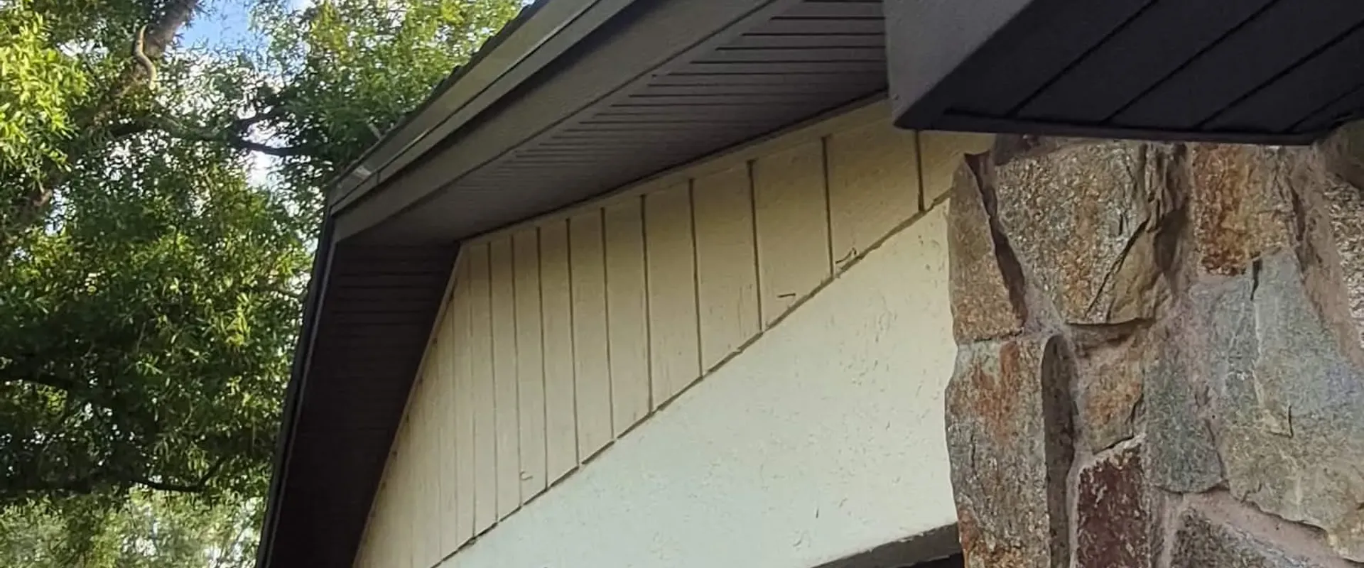 Dark brown soffit at a stone-and-stucco home gable with metal roof in St. Petersburg