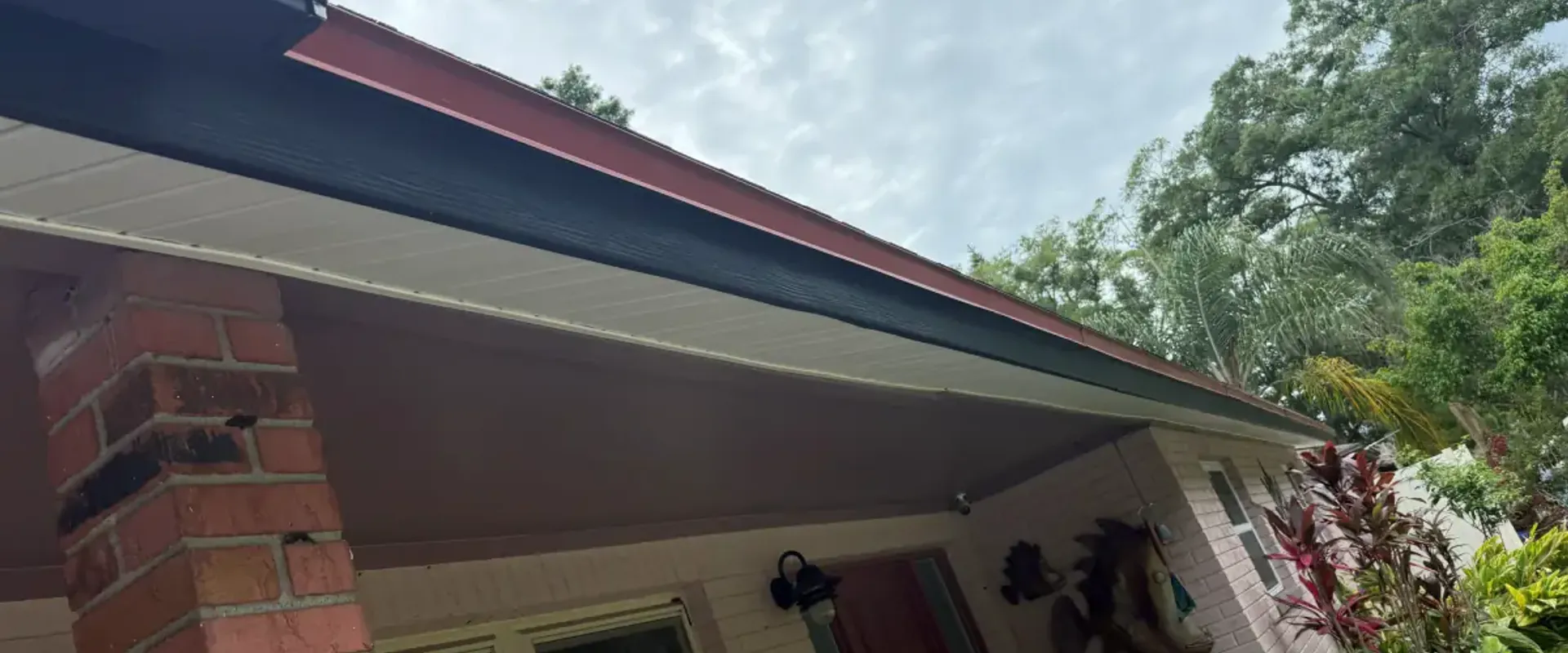White soffit and dark fascia over a brick-column front porch with a red door on a St. Petersburg home