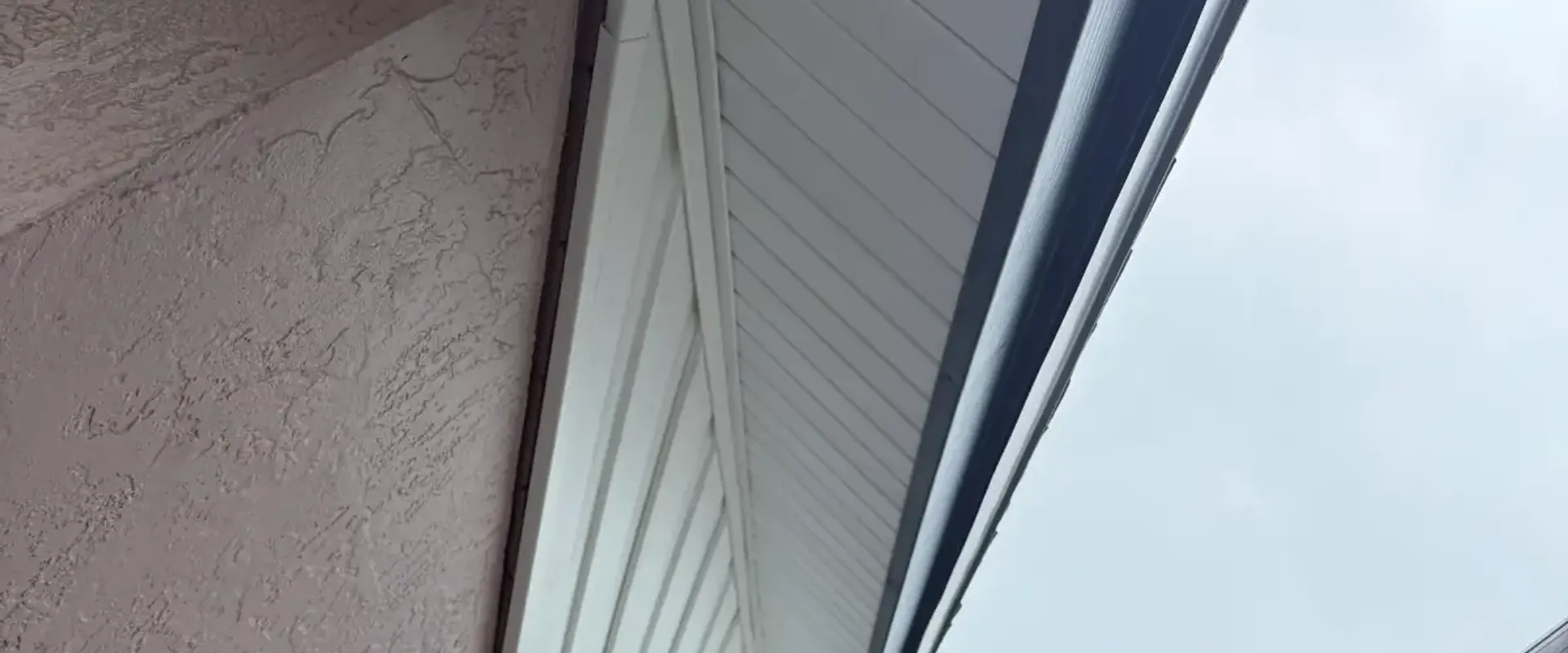 Mitered corner return of white soffit and navy aluminum fascia on a stucco St. Petersburg home