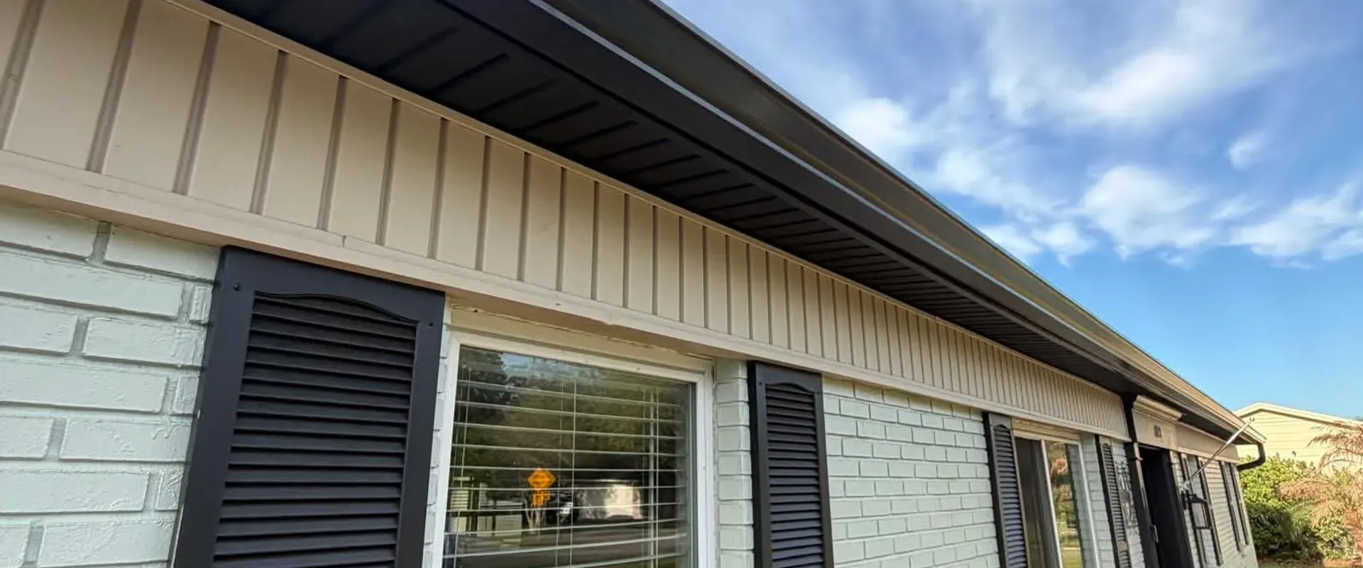 Crisp white vented soffit with dark gray fascia on a brick home with shutters