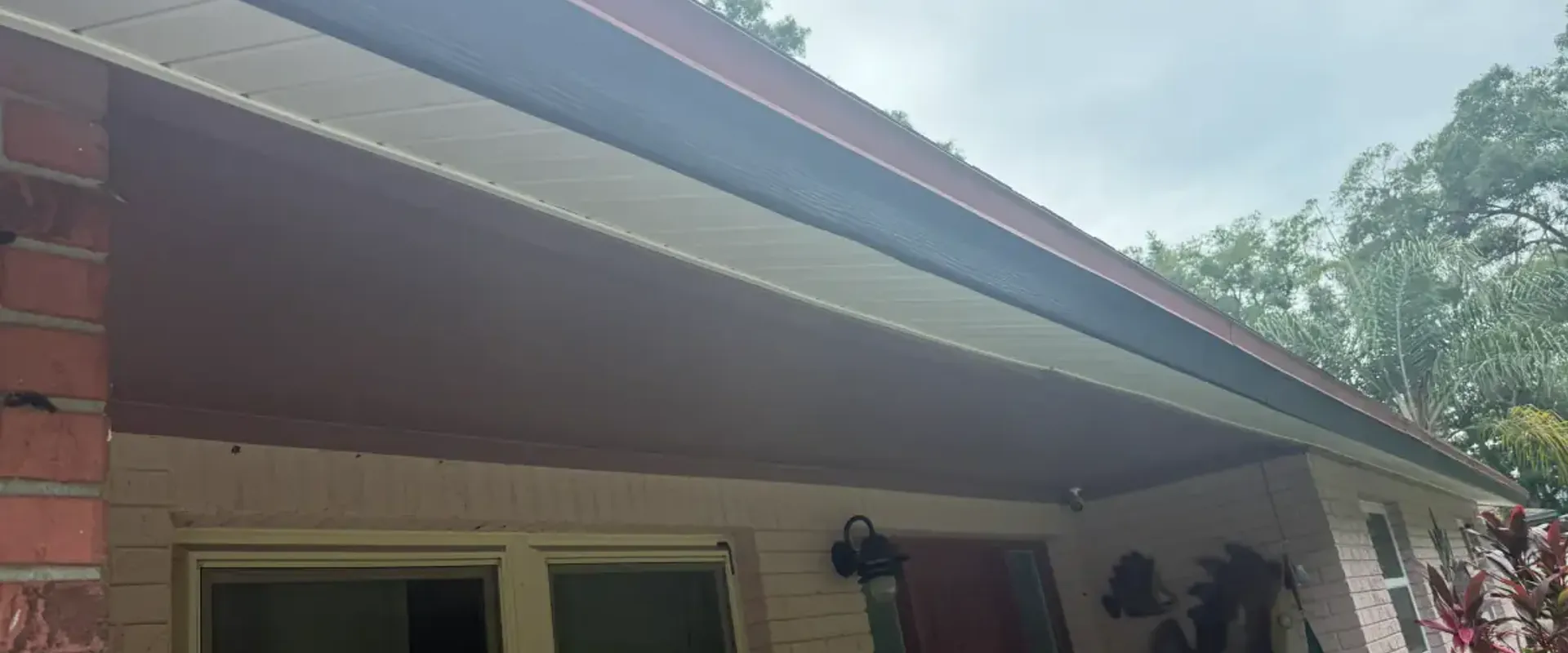 White vented soffit and dark fascia under the front porch eave of a brick ranch home in St. Petersburg