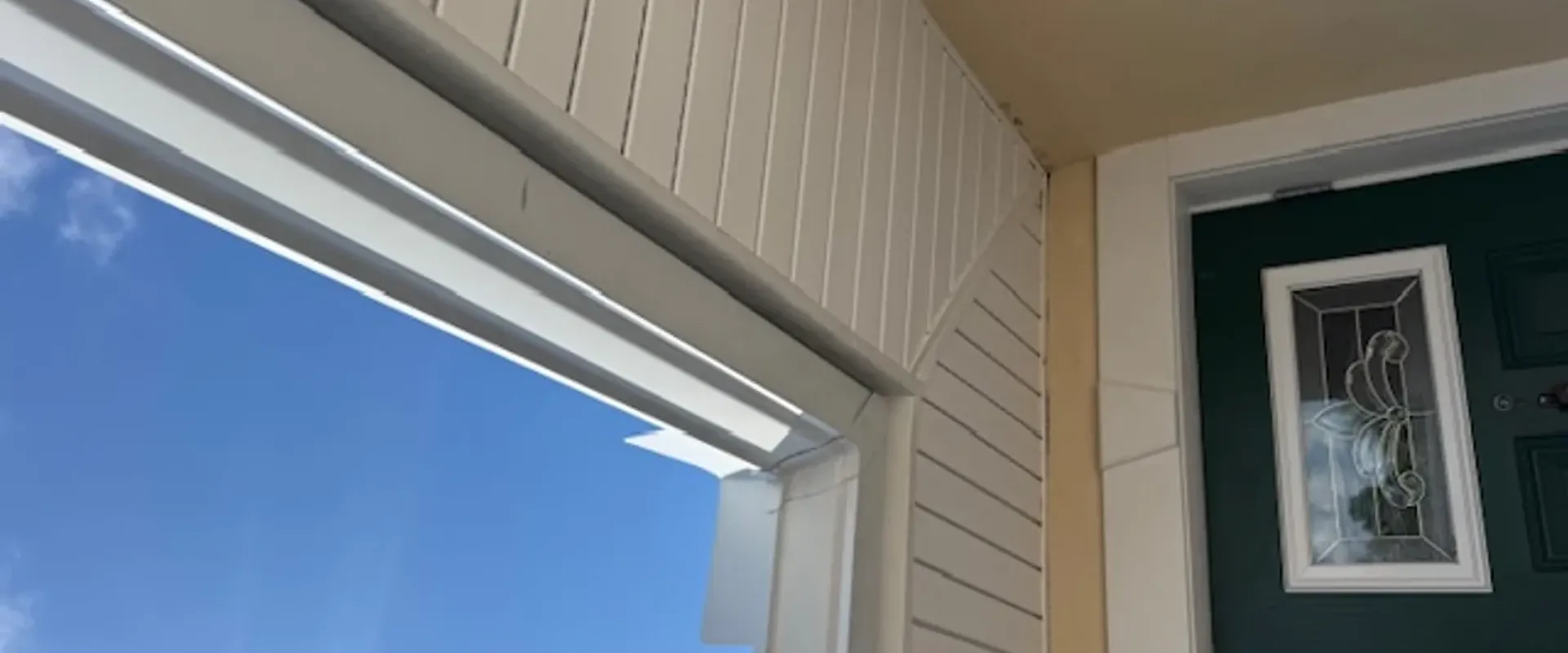 Crisp white soffit installed at the entryway of a Tampa Bay home with a green stained-glass front door and cream stucco