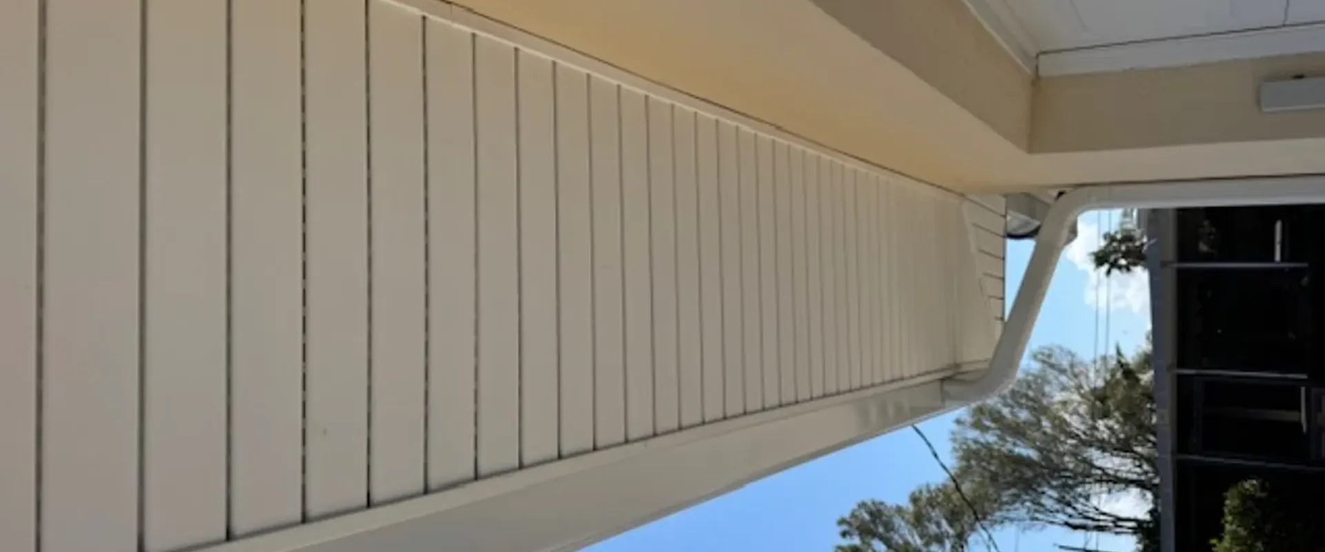 Clean white vented soffit running along a long overhang on a cream stucco Tampa home with a clear blue sky and palm trees
