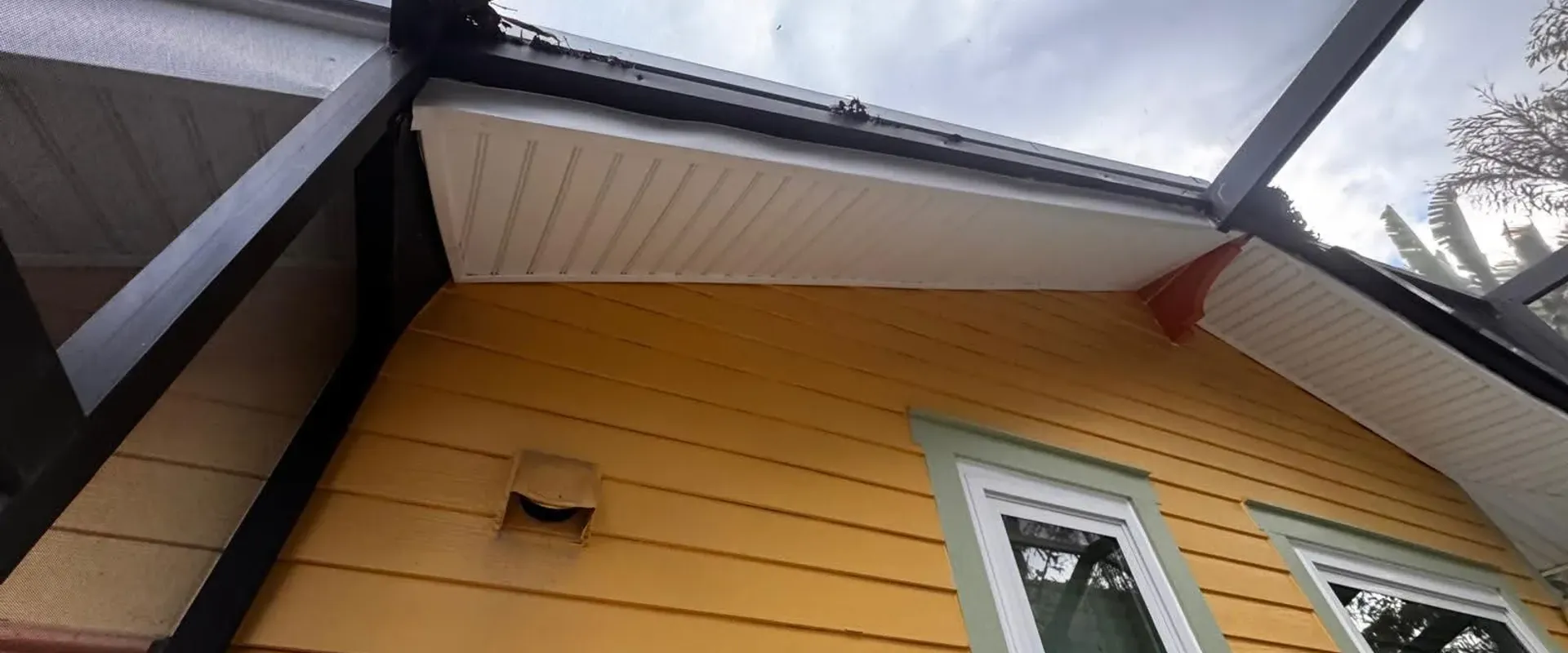Clean white soffit at a gable end on a yellow siding home with a screen enclosure in Tampa Bay
