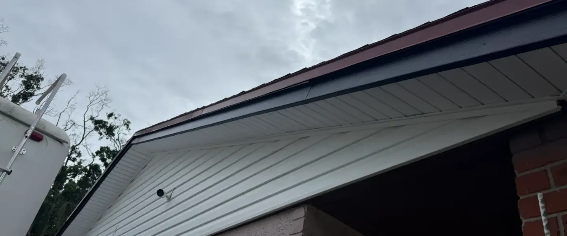 White vented soffit and navy fascia on a stucco gable-end carport at a St. Petersburg home