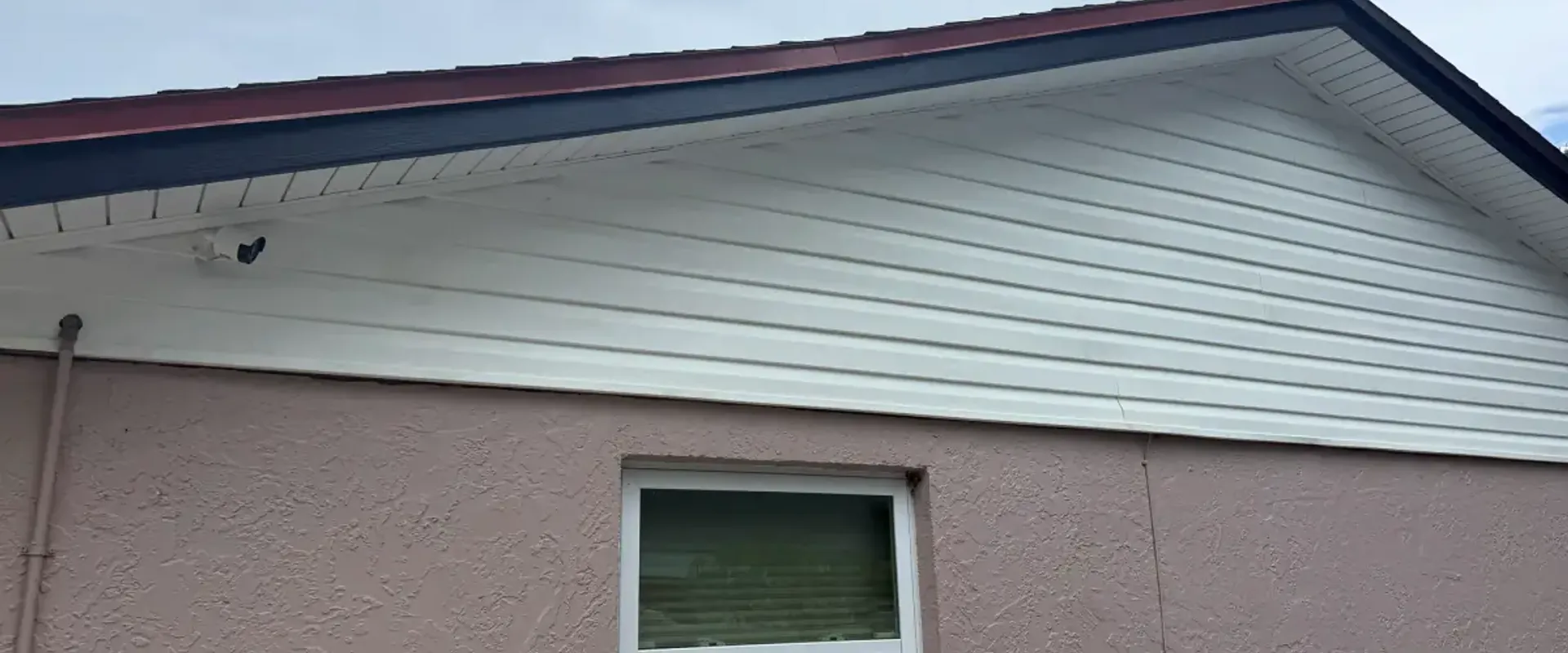 White vented soffit and navy fascia on the gable end of a blush stucco St. Petersburg home