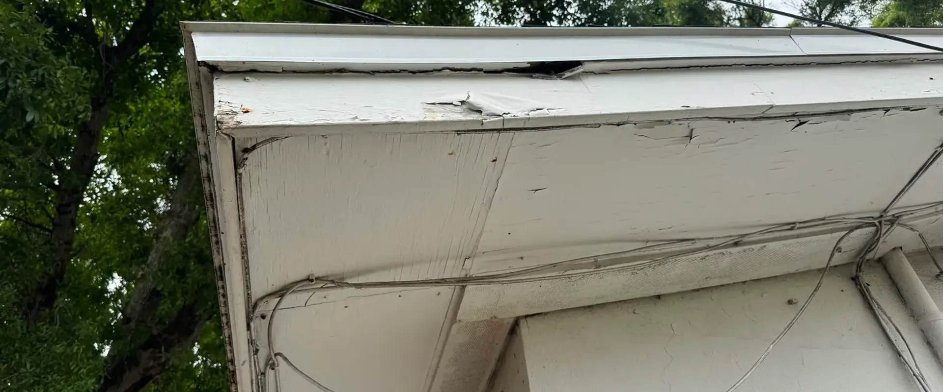 Old fascia at a corner with original exterior wiring, before professional renovation