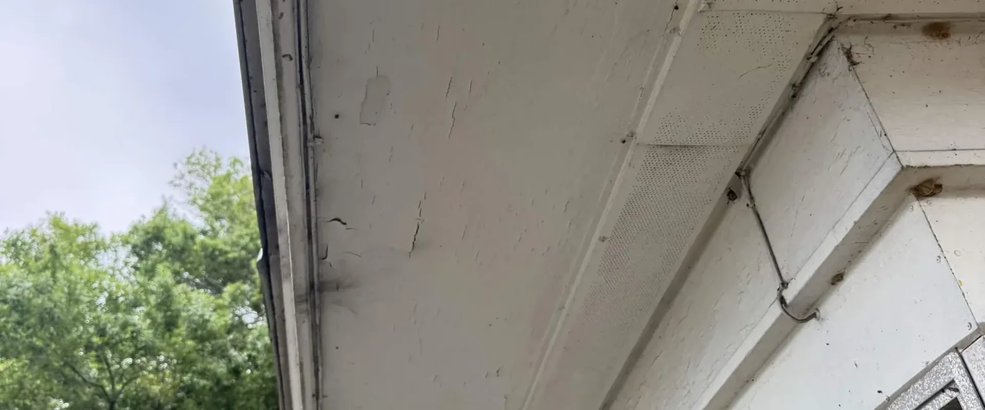 Discolored fascia with peeling paint adjacent to a screened porch, before aluminum wrap