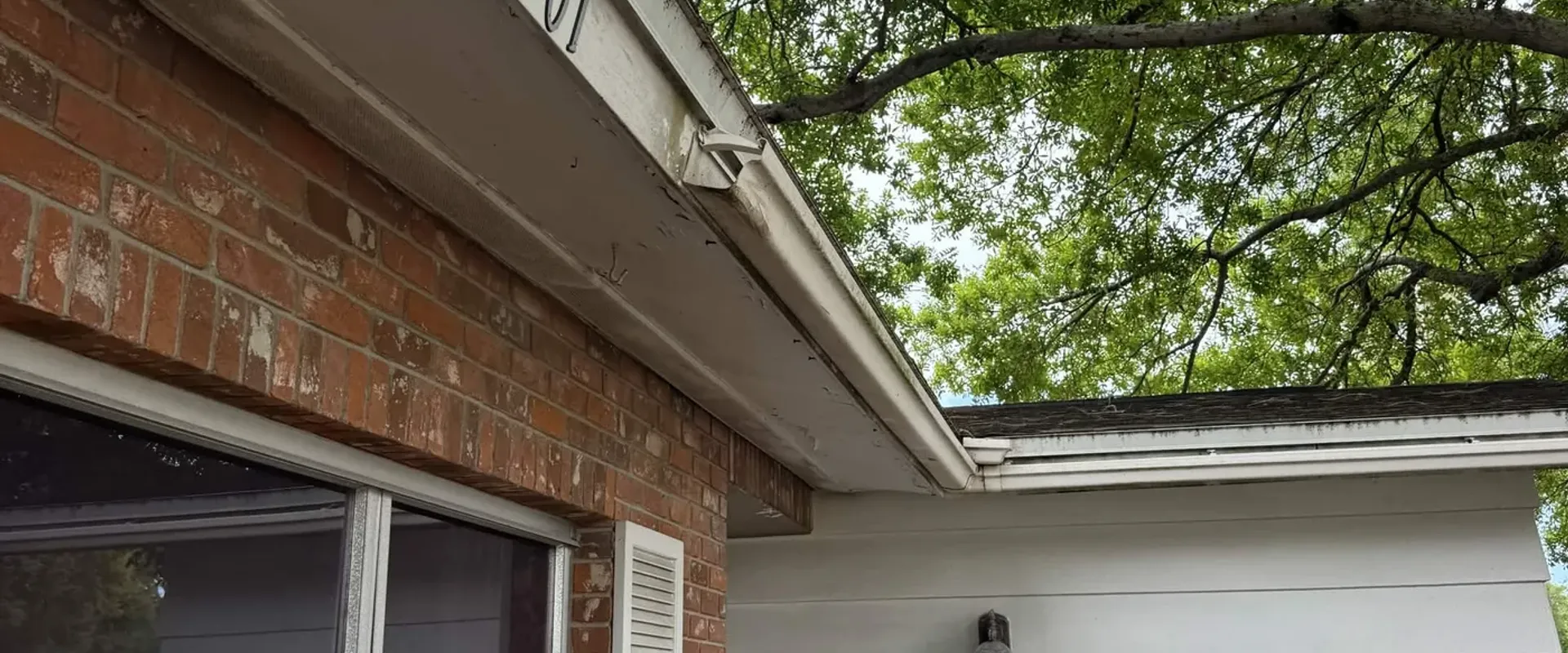 Distant view of weathered fascia and soffit at a gable peak, before exterior renovation