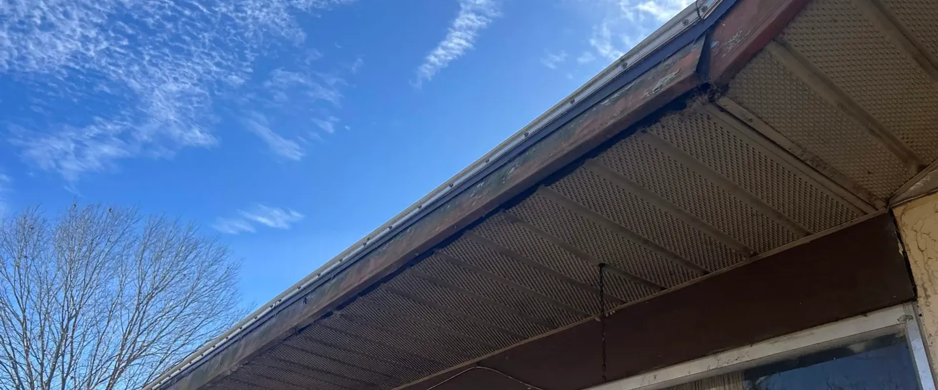 Rusty vented soffit on a neglected Tampa Bay building before professional renovation