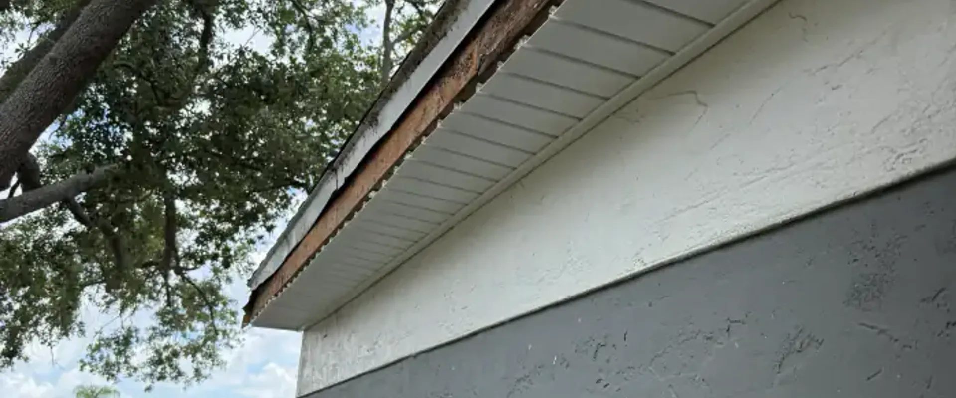 Weathered bare wood sub-fascia exposed mid-project before aluminum fascia wrap is installed over it
