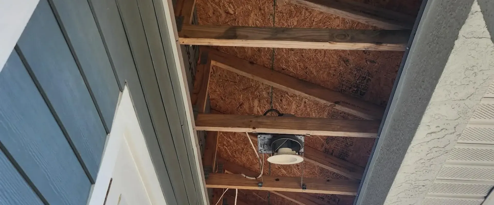 Wider view of exposed rafters being repaired before new soffit installation by LG Exteriors